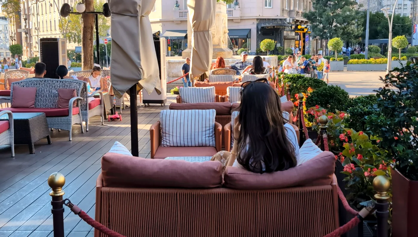 Une femme assise seule à la terrasse d'un café, de dos, un peu à l'écart